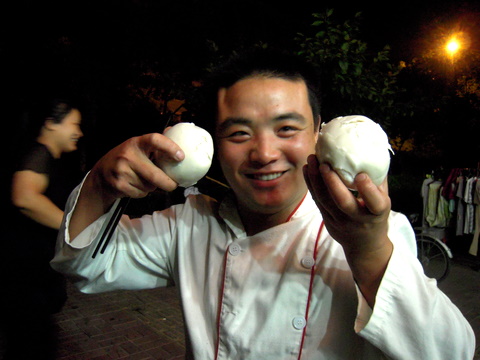 One of my new Chinese friends who cooks at the restaurant which serves the crayfish above. He's from Henan, along with the rest of the staff. Here, he's holding a steamed Chinese bread called "mantou." We're about to eat our tasty dinner of stewed lamb bone soup, see below.